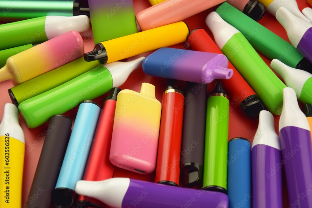 Set of multicolor disposable electronic cigarettes on a red background.